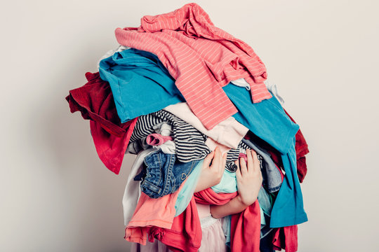 10 great reasons to hire a stylist, Pile of clothing, messy clothing, woman holding clothing, woman holding pile of clothing, unfolded laundry, pile of laundry